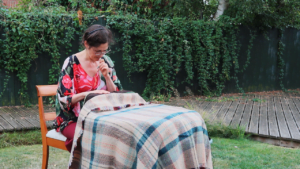 Cathy Hay sewing in a garden, August 2022